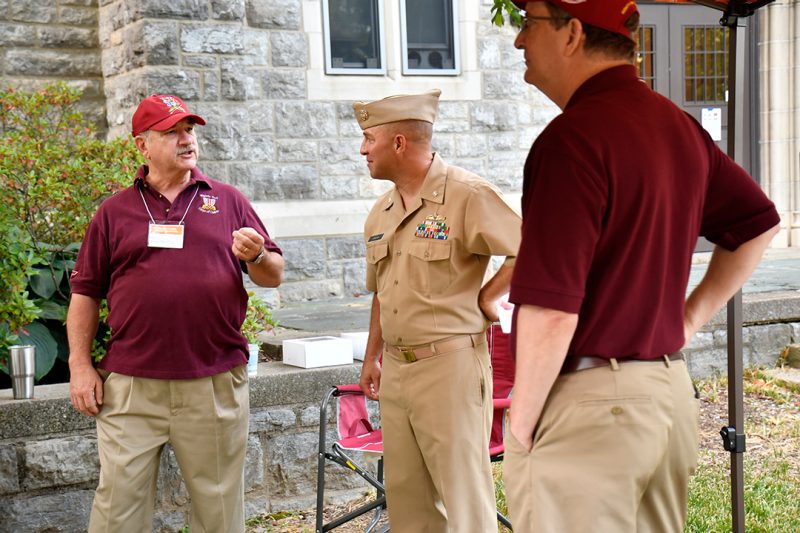 Cmdr. Nate Brown (at center), the new alumni director for the Corps, talks with two Highty-Tighty alumni .