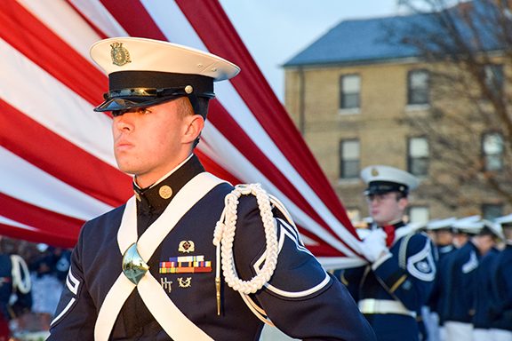 A cadet stands in front of an American flag.