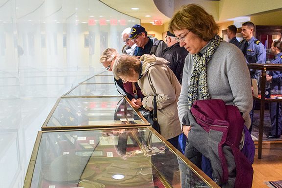 A crowd of people look at a museum case.